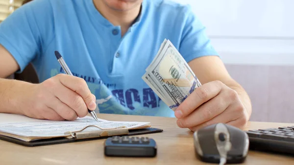 Uomo Maglietta Blu Che Conta Dollari Compila Modulo Delle Tasse — Foto Stock