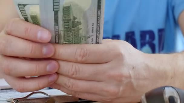 Man in blue T-shirt counting dollars and filling tax form — Stock Video