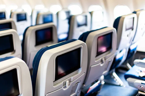 Aircraft interior with seats and blank touch screens displays. — Stock Photo, Image