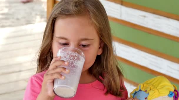 Una niña bebe un cóctel de leche de vainilla. — Vídeo de stock