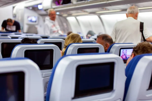 Aircraft interior with seats and blank touch screens displays.