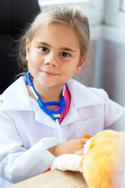 Милая девочка, играющая в доктора с плюшевой игрушкой — стоковое фото