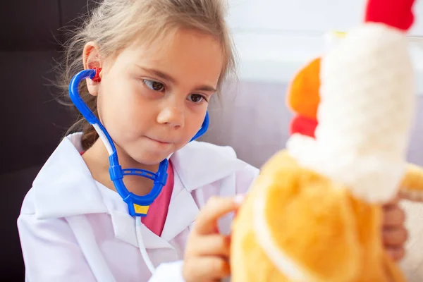 Cute child girl playing doctor with plush toy