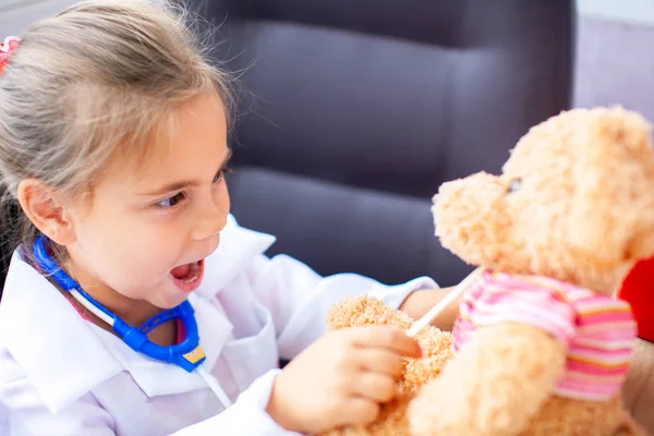 Милая девочка, играющая в доктора с плюшевой игрушкой — стоковое фото