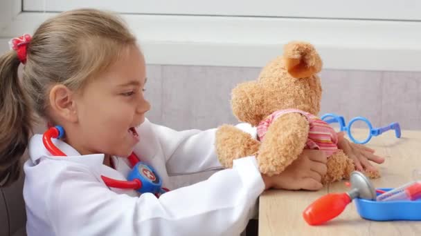 Cute child girl playing doctor with teddy bear — Stock Video