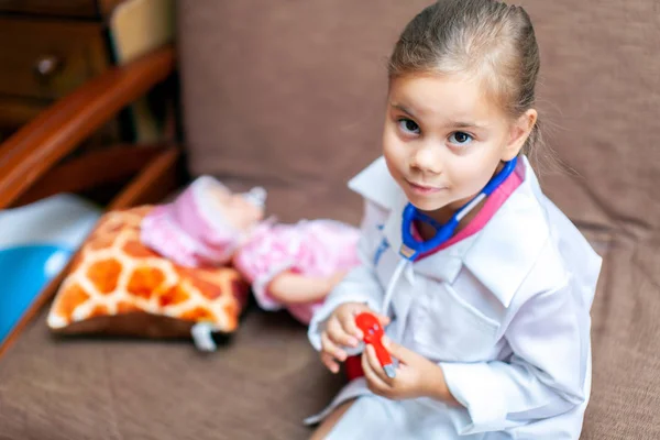 Menina bonito jogando médico com brinquedo boneca bebê — Fotografia de Stock