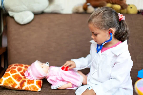 Симпатичная девочка, играющая врача с детской игрушкой — стоковое фото