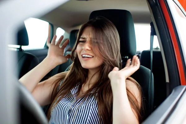 Giovane donna che si tocca la testa per mano mentre è seduta in macchina . — Foto Stock