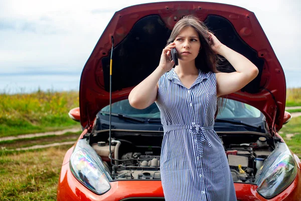 Mulher com um carro quebrado na estrada rural está chamando no telefone celular. — Fotografia de Stock