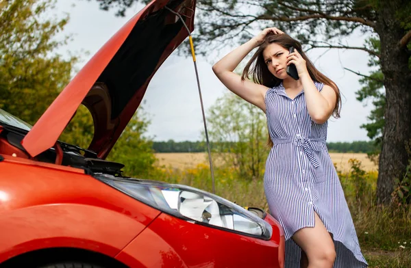 田舎道で壊れた車の女が携帯電話で電話をかけてる. — ストック写真