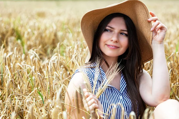 Mladá krásná žena, která se opírá o zlaté pole pšenice — Stock fotografie