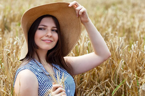 Young beautiful woman resting on golden field of wheat — Stock Photo, Image