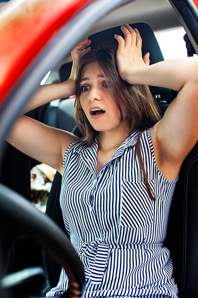 Νεαρή γυναίκα αγγίζει το κεφάλι της με τα χέρια ενώ κάθεται σε ένα αυτοκίνητο. — Φωτογραφία Αρχείου