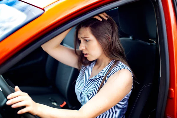 Junge Frau berührt ihren Kopf mit den Händen, während sie im Auto sitzt. — Stockfoto