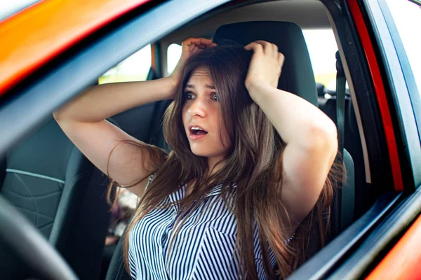 Junge Frau berührt ihren Kopf mit den Händen, während sie im Auto sitzt. — Stockfoto