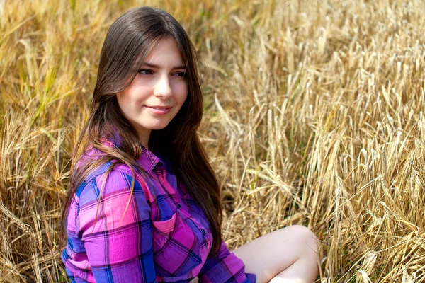 Young country woman in plaid shirt possing in a field of wheat — Stock Photo, Image