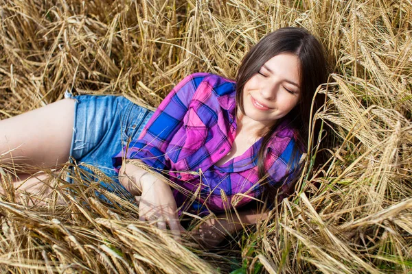 Junge Landfrau im karierten Hemd posiert in einem Weizenfeld — Stockfoto