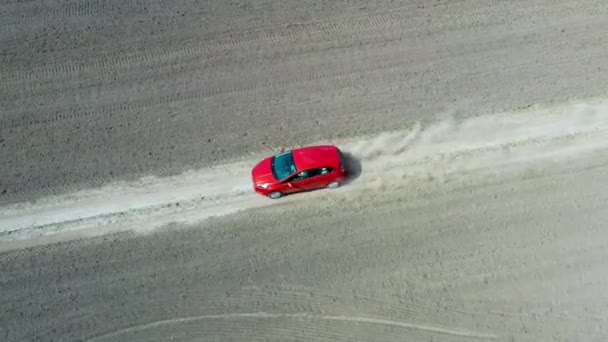 Vista aérea desde el avión no tripulado en un coche rojo que conduce a lo largo de la carretera de grava vacía — Vídeos de Stock