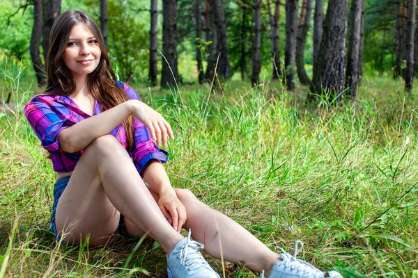 Jeune femme assise dans une forêt de pins — Photo