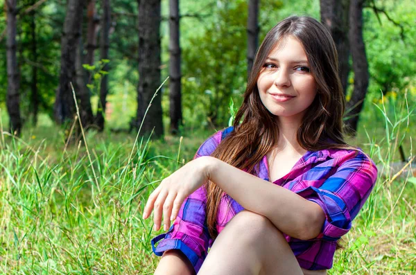 Young woman sitting in a pine tree forest — Stock Photo, Image