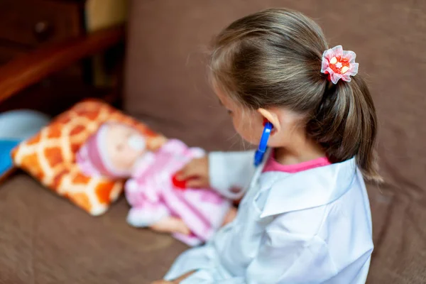 Menina bonito jogando médico com brinquedo boneca bebê — Fotografia de Stock