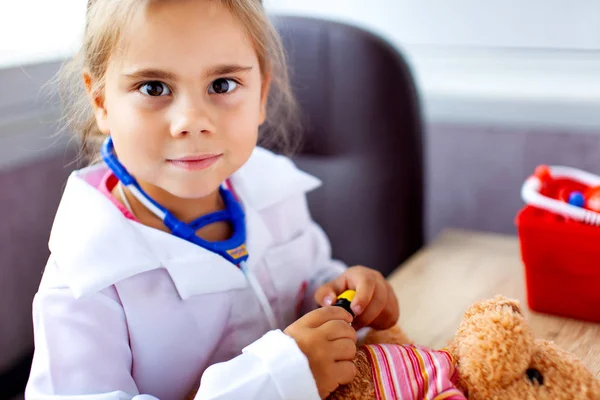 Menina bonito jogando médico com brinquedo de pelúcia — Fotografia de Stock