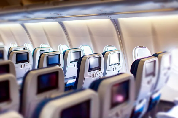 Интерьер самолета с сиденьями и чистыми сенсорными экранами. — стоковое фото