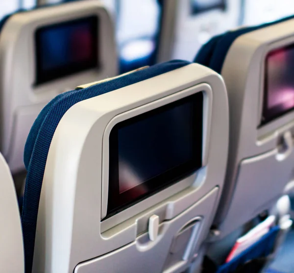 Aircraft interior with seats and blank touch screens displays. — Stock Photo, Image