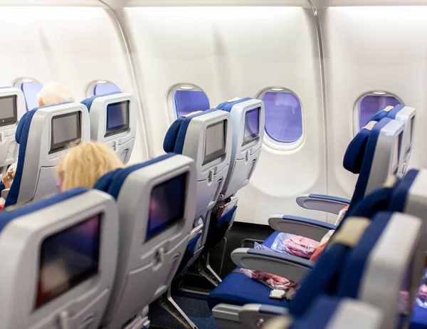 Aircraft interior with seats and blank touch screens displays.