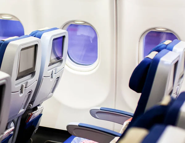 Aircraft interior with seats and blank touch screens displays.