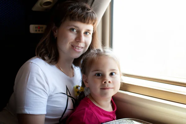 Petite fille enfant et sa mère regardant par la fenêtre dans le train . — Photo