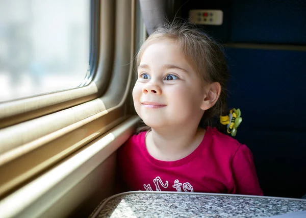 Μικρό κορίτσι κοιτάζει μέσα από το παράθυρο του τρένου — Φωτογραφία Αρχείου