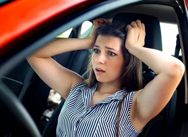 Mladá žena dotýká její hlavu rukama, zatímco ona sedí v autě. — Stock fotografie