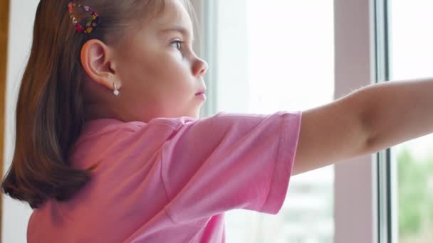 Портрет ребенка, смотрящего в окно — стоковое видео