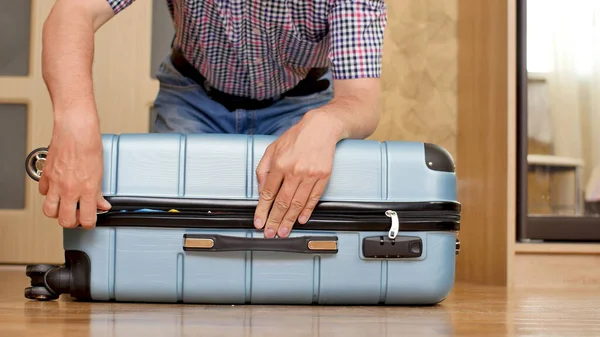 Чоловік намагається упакувати переповнену валізу — стокове фото