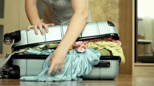 Mujer joven tratando de empacar una maleta llena — Vídeo de stock