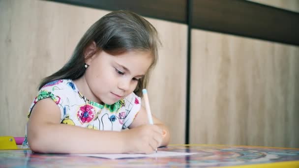 Uma menina ou bonito primário criança escola criança pintura ou escrita em papel . — Vídeo de Stock