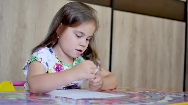 Uma menina ou bonito primário criança escola criança pintura ou escrita em papel . — Vídeo de Stock