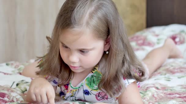 Petit bébé heureux joue tablette tout en étant couché sur le lit. — Video