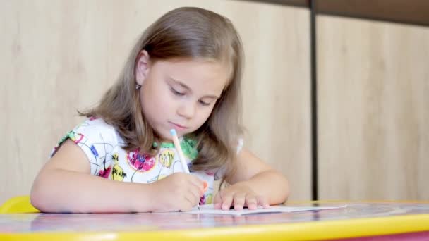 Uma menina ou bonito primário criança escola criança pintura ou escrita em papel . — Vídeo de Stock