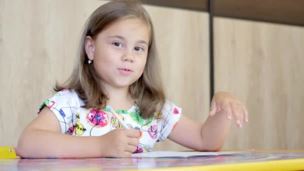 Uma menina ou bonito primário criança escola criança pintura ou escrita em papel . — Vídeo de Stock