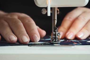 Evde dikiş makinesini kullanan kadın elleri