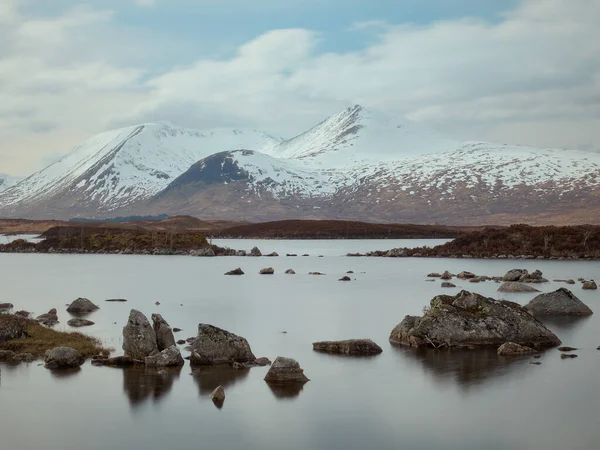 Un lago de montaña en las tierras altas escocesas con piedras en el agua —  Fotos de Stock