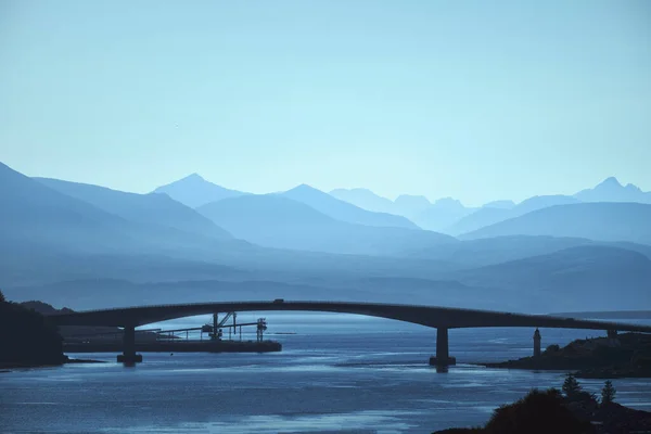 Silhuett av bågbron över sjön mot bakgrund av vackra berg — Stockfoto