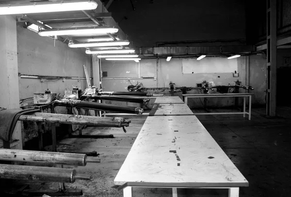 Black and white photo of the abandoned and traditional workshop. Sewing and dyeing clothes and jeans with roses on the wall.