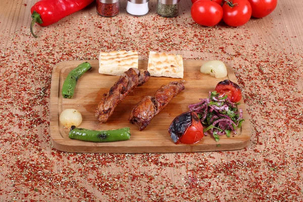 Kebabs de carne asada turca y verduras frescas en una mesa de madera — Foto de Stock