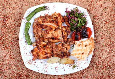 Kızarmış tavuk, yeşil pepperonili beyaz bir tabakta servis edilir.