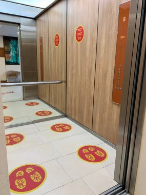 Asansörün zemininde sosyal mesafe işaretleri var.