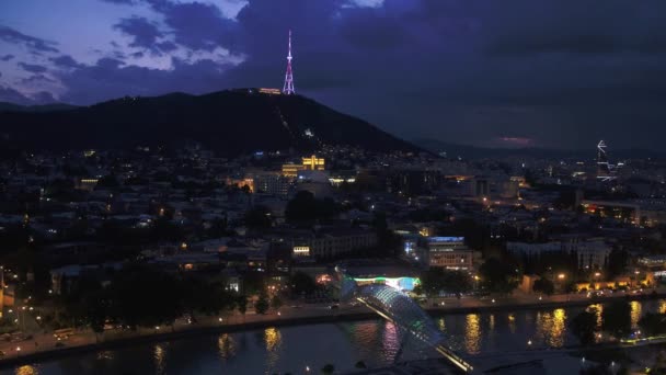 Tbilisi, Georgië - juni 2018: stad 's nachts, Kura rivier, Peace Bridge en Tbilisi Tv toren. Schieten vanaf een hoogte — Stockvideo