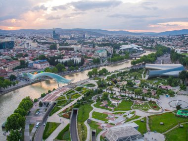 Tiflis, Gürcistan - Haziran 2018: Rike Park, Kura Nehri ve Barış Köprüsü gün batımında, havadan görünüm